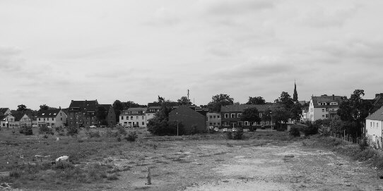 Blick vom höchsten Punkt des Lärmschutzwalls der Brache am Ende der Godehardstraße in Bremen, Hemelingen, auf eine Statue (unterer Bildrand Mitte) und einen winzigen Unterstand mit einer hellen Plastikplane (unterer Bildrand rechts)