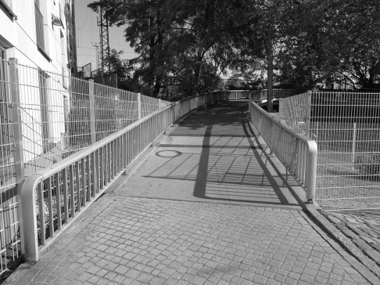 Detail 3: Zaun am Aufgang der Fußgängerbrücke vor der Flanke des Hotels