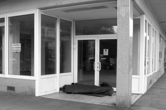 Obdachloser im Eingangsbereich eines leerstehenden Geschäftslokals