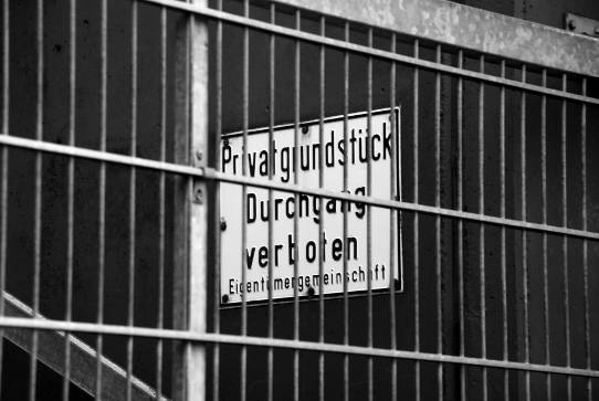 Verbotsschild hinter Umzäunung des Außengeländes eines Hochhauses mit vielen Eigentumswohnungen